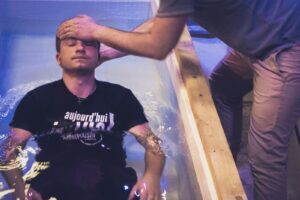 man in black crew neck t-shirt and blue cap standing beside swimming pool